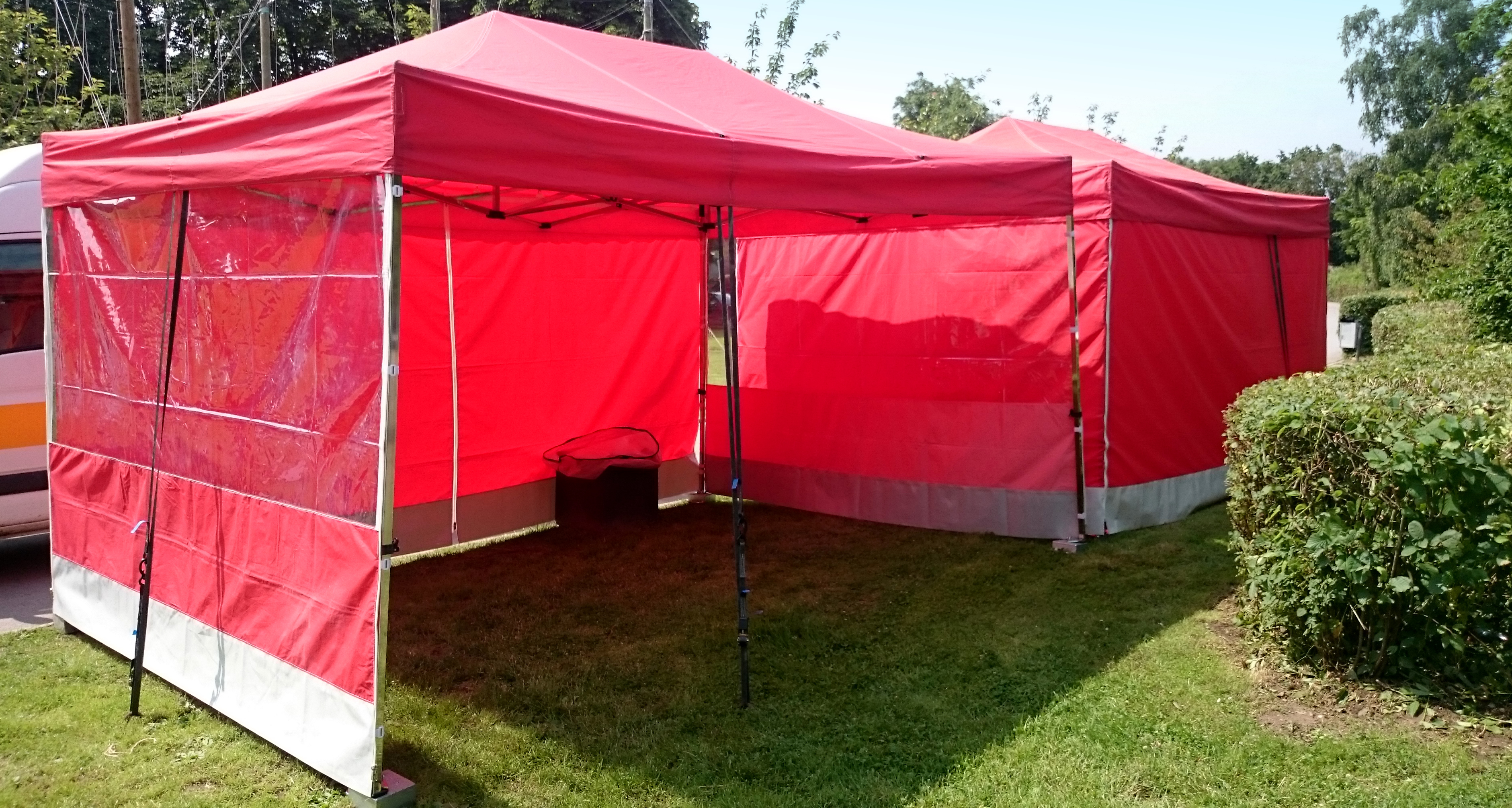 Zwei rote Faltpavillons für Marktstände auf einem großen Sommerfest