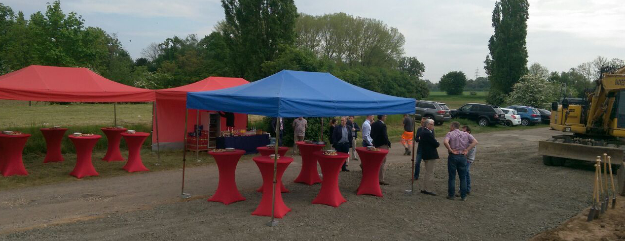 Stehtisch mit roter Busse auf einer Grundsteinlegung bzw. Richtfest