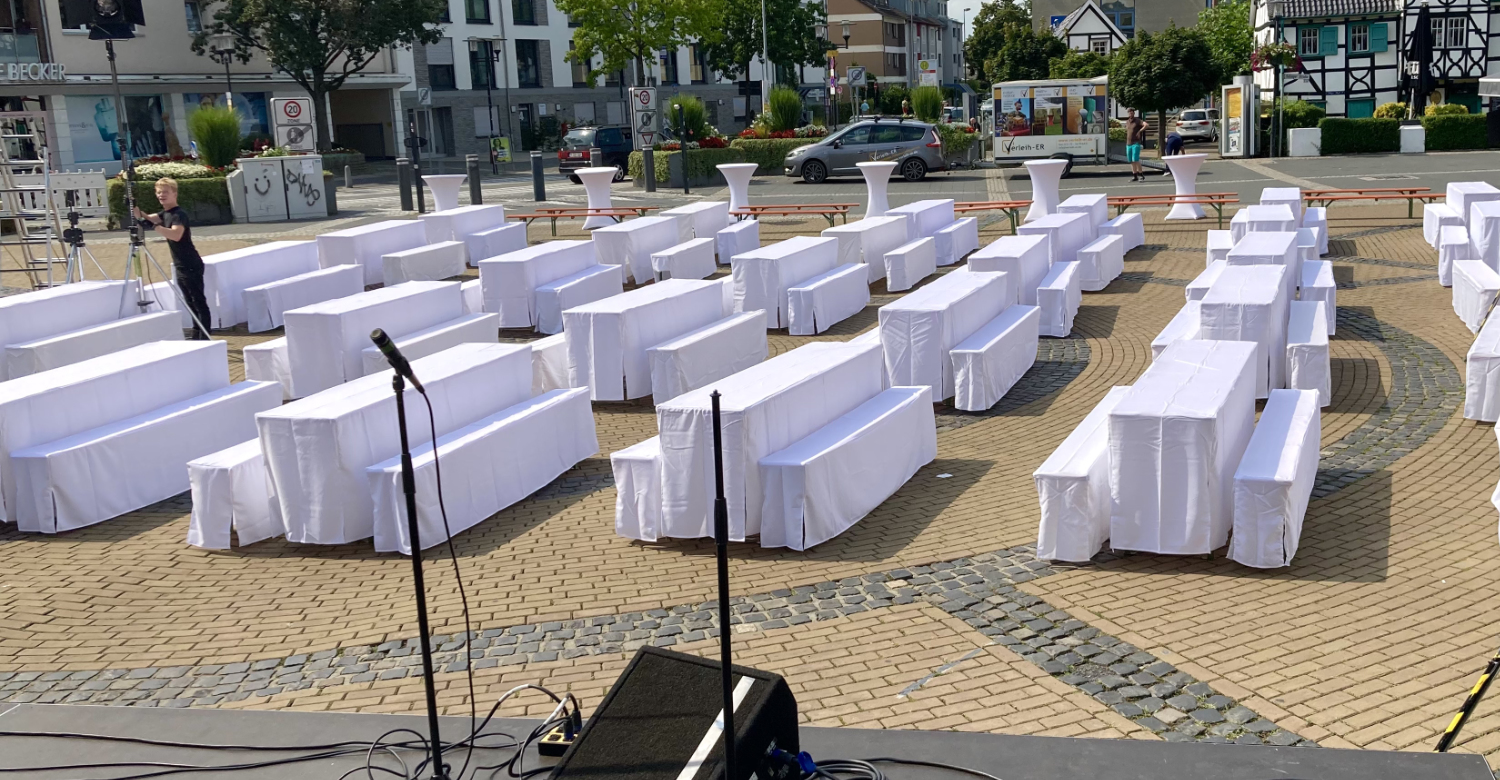 Viele Bierzeltgarnituren mit Hussen für eine Kulturveranstaltung auf einem Marktplatz